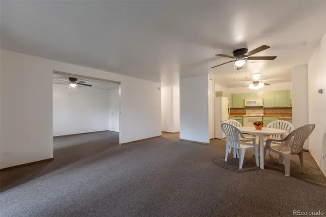 a dining room with furniture and a chandelier fan