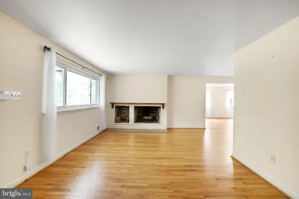 a view of an empty room with window and wooden floor