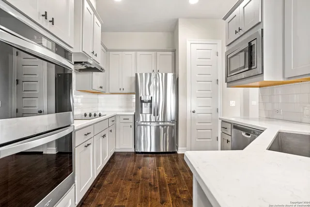 a kitchen with stainless steel appliances granite countertop a refrigerator a stove and a sink