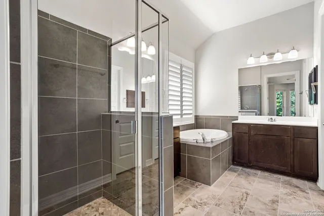 a bathroom with a sink vanity granite tub shower and a mirror