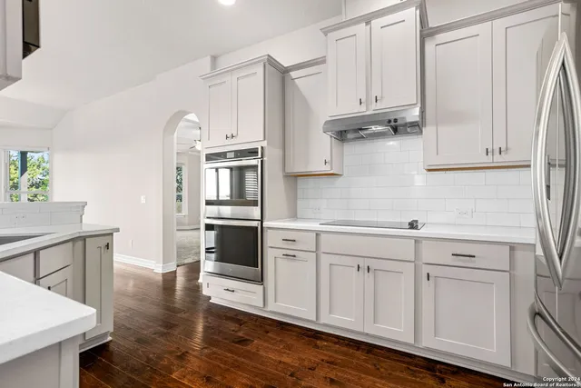 a kitchen with stainless steel appliances granite countertop a refrigerator and white cabinets