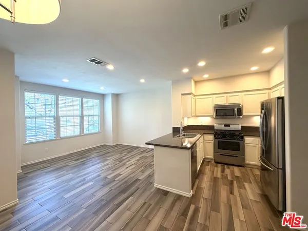 a kitchen with stainless steel appliances a stove top oven a sink and a refrigerator