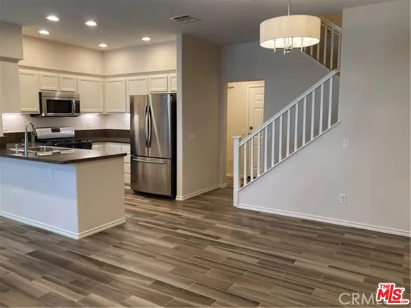 a view of kitchen with stainless steel appliances granite countertop stove top oven and refrigerator