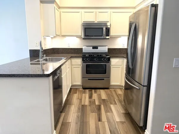 a kitchen with a sink a refrigerator and a stove top oven