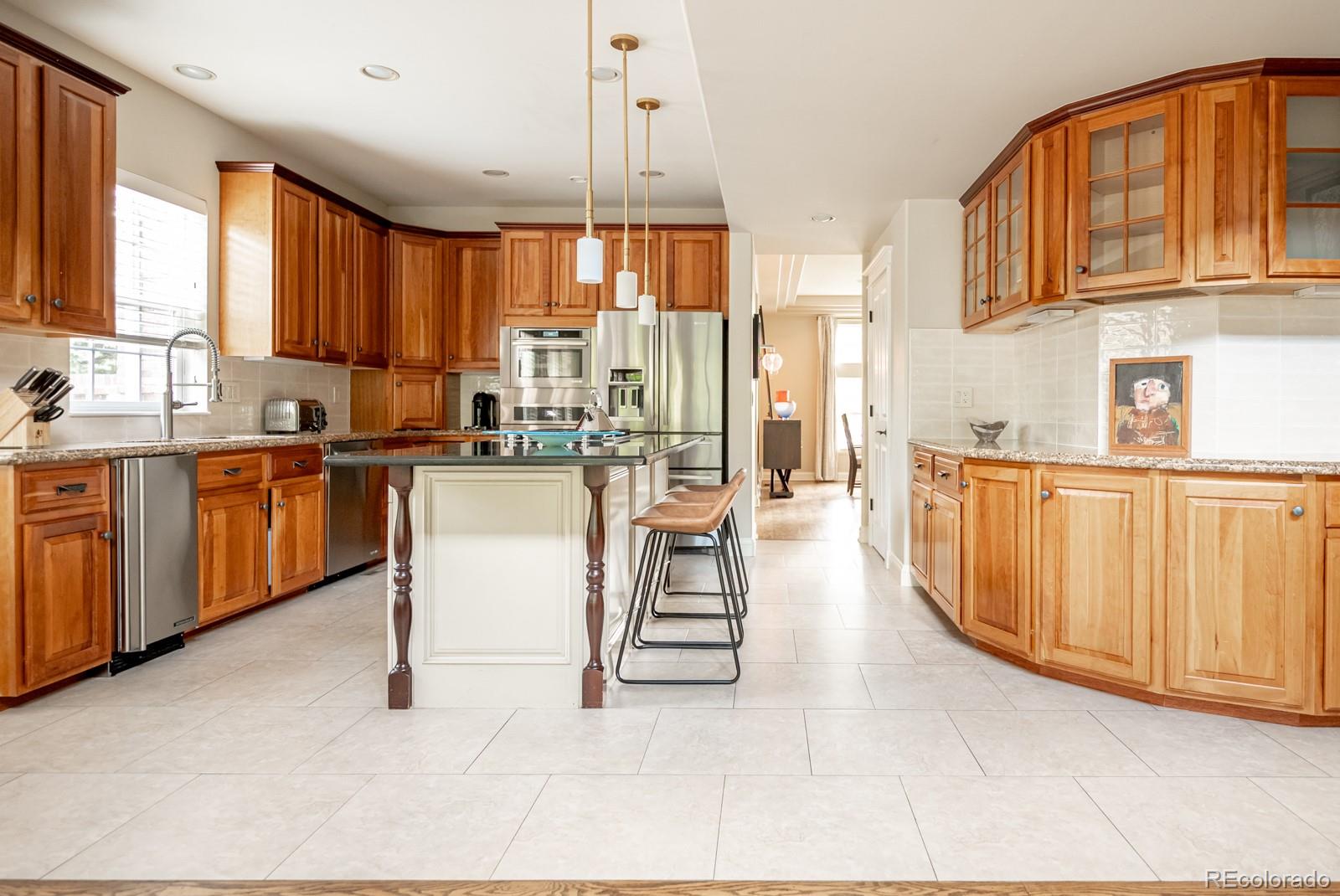 3350 Oak Street Wheat Ridge, CO 80033 - Photo 13 of 40 a open kitchen with stainless steel appliances granite countertop a stove top oven a sink dishwasher and white cabinets with wooden floor