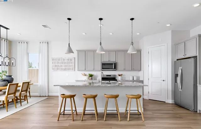 a kitchen with stainless steel appliances kitchen island granite countertop a dining table chairs and sink