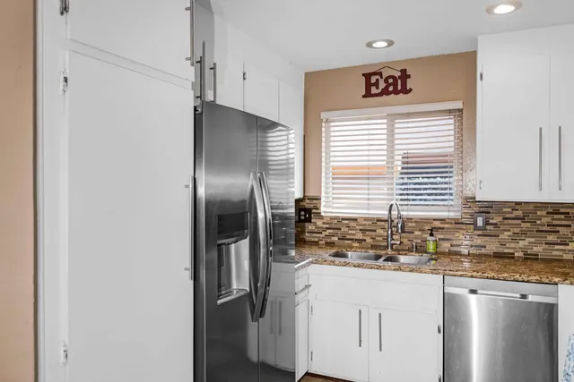 a kitchen with stainless steel appliances granite countertop a refrigerator and a sink