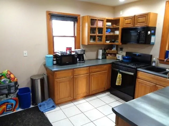 a kitchen with stainless steel appliances a stove a sink a microwave cabinets and a window