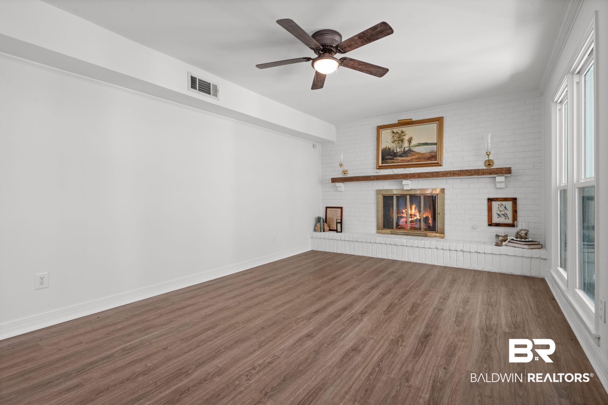 511 Wacker Lane North Mobile, AL 36608 - Photo 16 of 45 Unfurnished living room featuring dark wood-style flooring, brick wall, a fireplace, and a ceiling fan