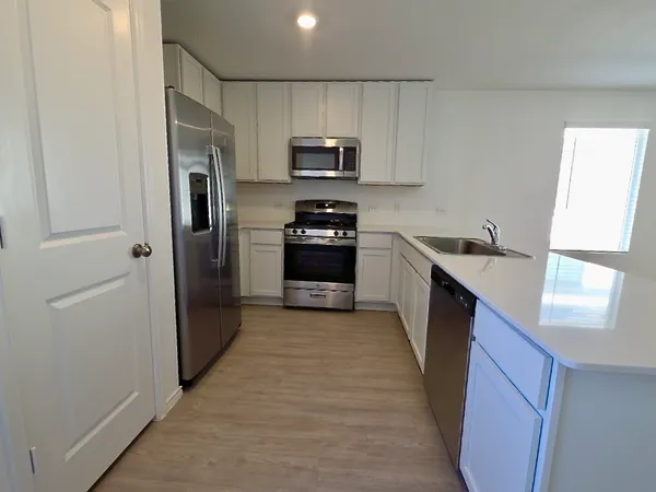 a kitchen with a sink a refrigerator and a stove top oven