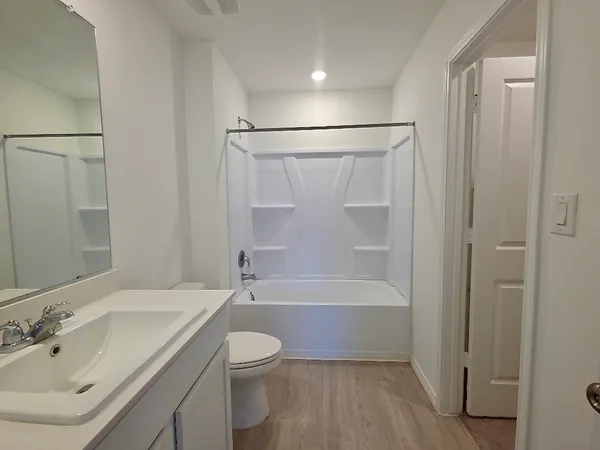 a bathroom with a bathtub shower sink vanity and toilet