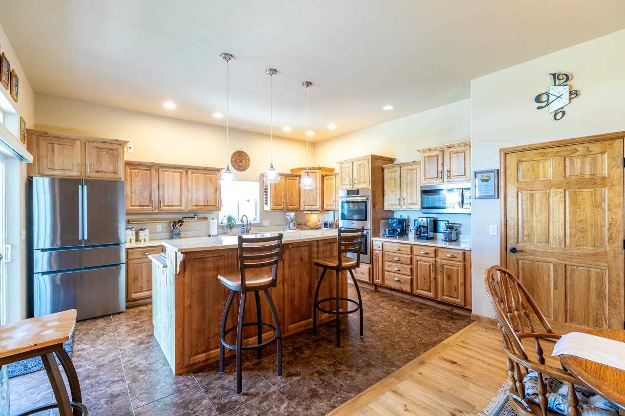 962 Hickory Street Fruita, CO 81521 - Photo 6 of 35 a kitchen with stainless steel appliances granite countertop a refrigerator a sink dishwasher a dining table and chairs with wooden floor