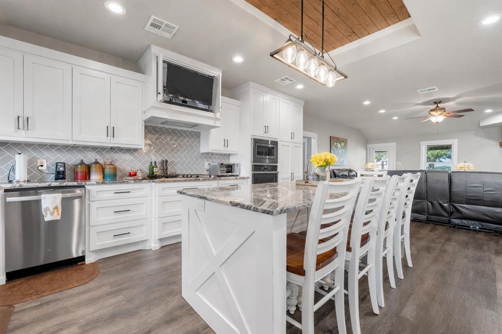 11541 Old Dallas Road West, TX 76691 - Photo 2 of 39 a kitchen with stainless steel appliances kitchen island granite countertop a stove top oven a sink a dining table and chairs with wooden floor