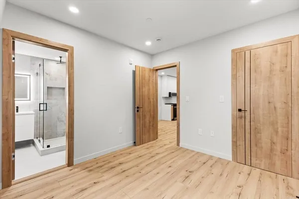 a view of empty room with wooden floor and fan