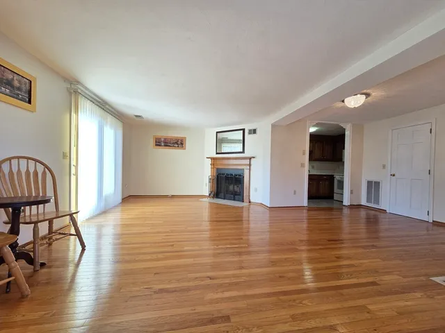 a view of empty room with wooden floor and fireplace