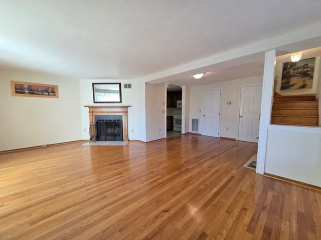 an empty room with wooden floor and fireplace