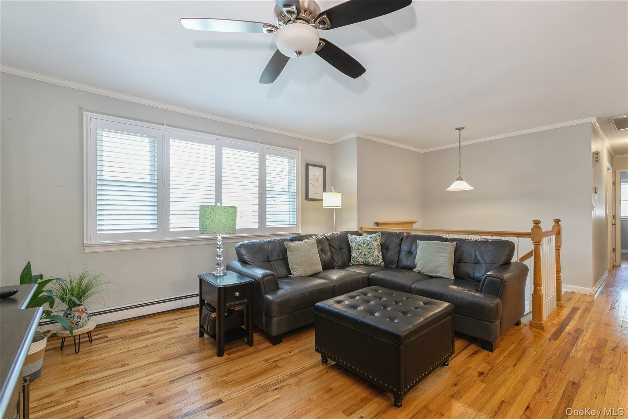 115 Clarendon Road Ronkonkoma, NY 11779 - Photo 6 of 45 Living area featuring wood-finish flooring, a multi-pane window with horizontal blinds, and a ceiling fan with integrated lighting