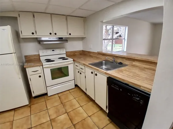 a kitchen with granite countertop a sink a stove and cabinets