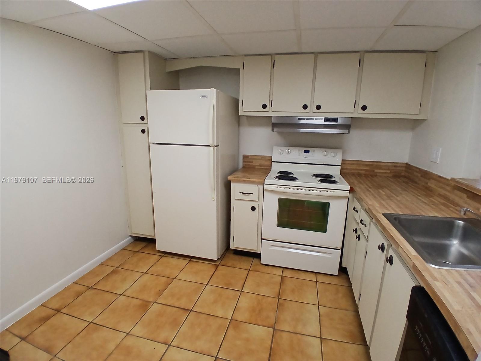 11273 Southwest 88th Street, Unit 114J Miami, FL 33176 - Photo 4 of 19 a kitchen with a stove top oven and cabinets