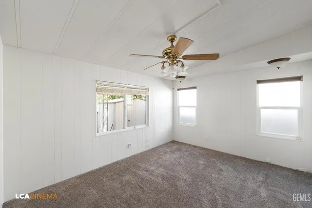 an empty room with a window and a chandelier fan