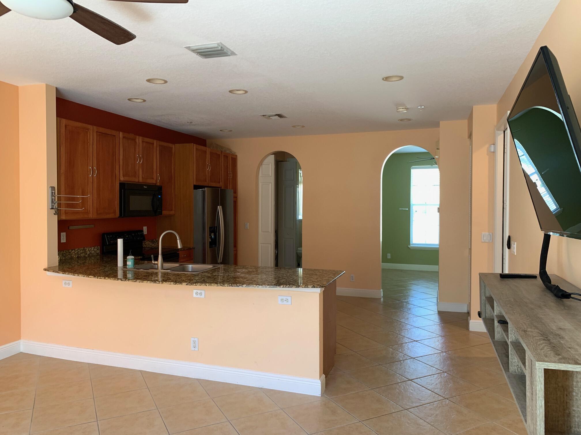 145 Morning Dew Circle Jupiter, FL 33458 - Photo 3 of 12 a view of a kitchen with kitchen island a sink a counter top space and stainless steel appliances