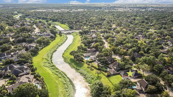 an aerial view of a house with swimming pool and large trees