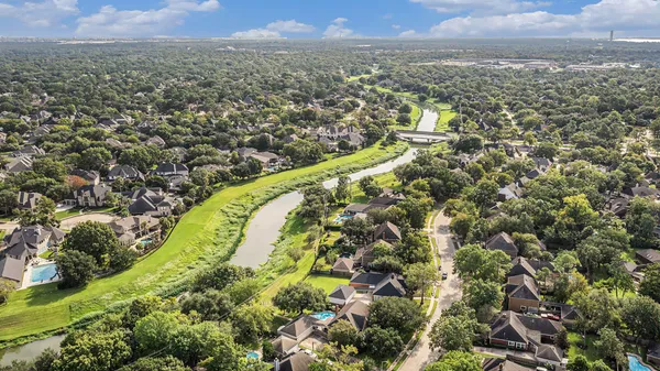 an aerial view of residential houses with outdoor space and trees