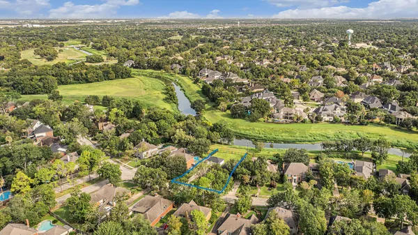 an aerial view of residential houses with outdoor space and trees