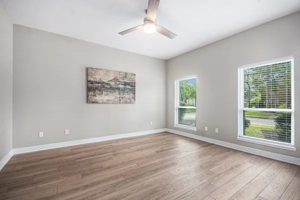 a view of an empty room with wooden floor and a window