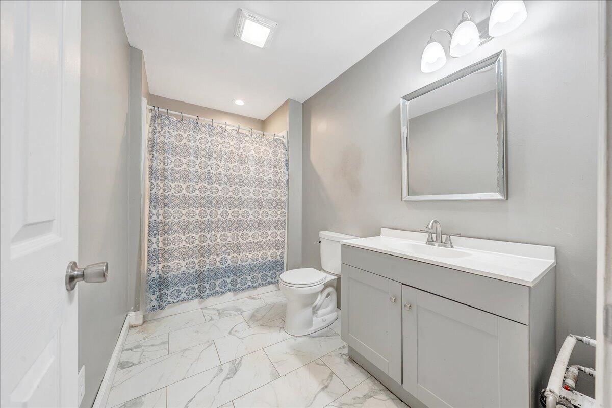 6379 Fork Mountain Road Rocky Mount, VA 24151 - Photo 6 of 9 a bathroom with a toilet a sink a mirror a shower and vanity