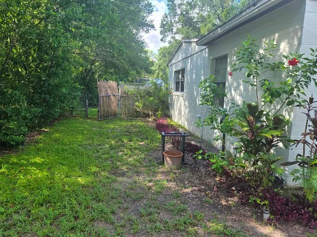 a backyard of a house with table and chairs plants