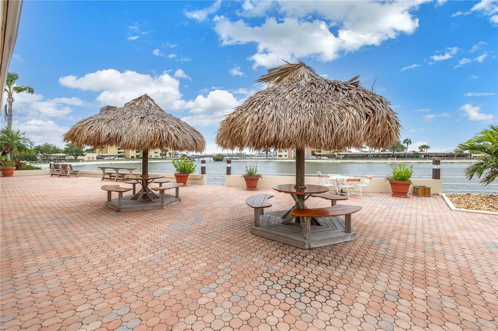 4525 Cove Circle, Unit 102 St. Petersburg, FL 33708 - Photo 63 of 73 a view of a patio with a table and chairs under an umbrella with a fire pit