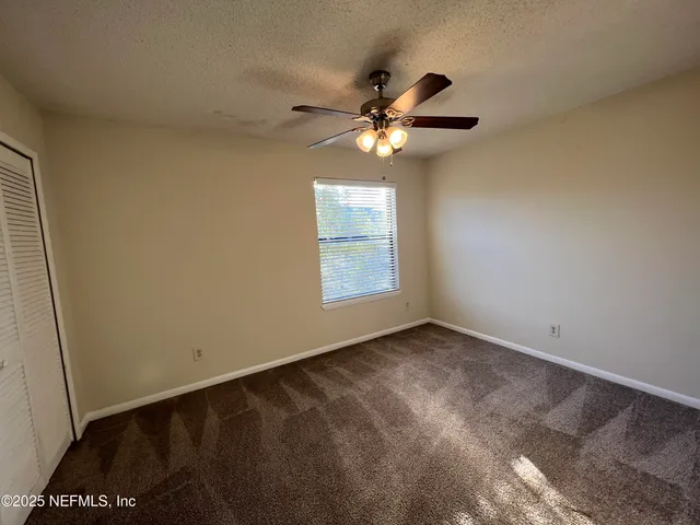 an empty room with windows and fan