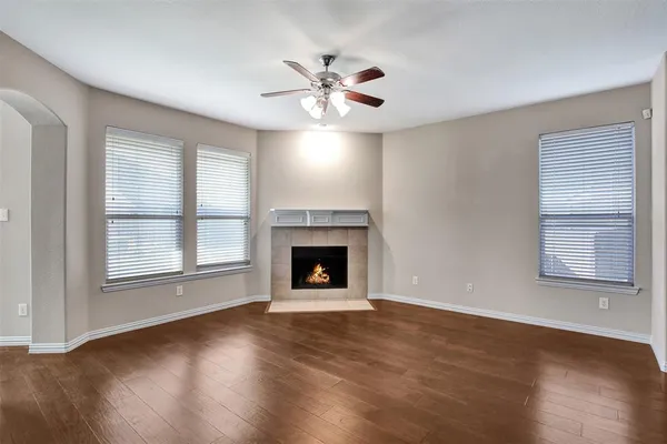a view of an empty room with wooden floor fireplace and a window