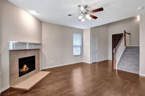 a view of an empty room with wooden floor fireplace and a window