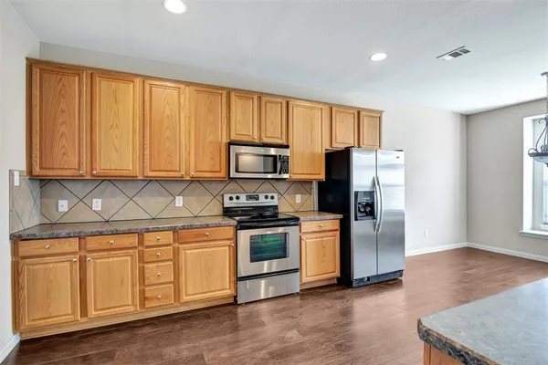 a kitchen with stainless steel appliances granite countertop a refrigerator a stove top oven a sink and dishwasher with wooden floor