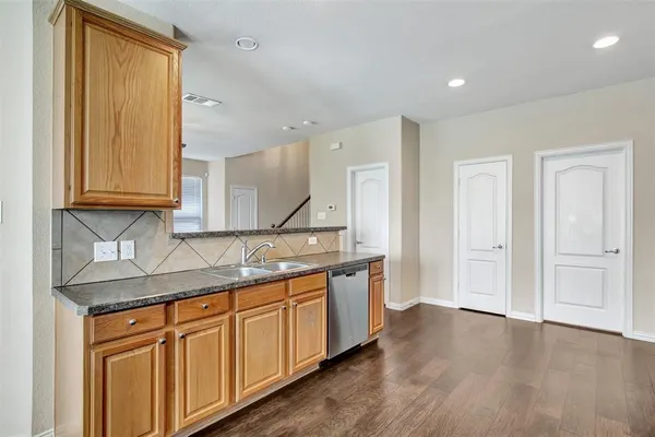 a kitchen with stainless steel appliances granite countertop a sink and cabinets with wooden floor
