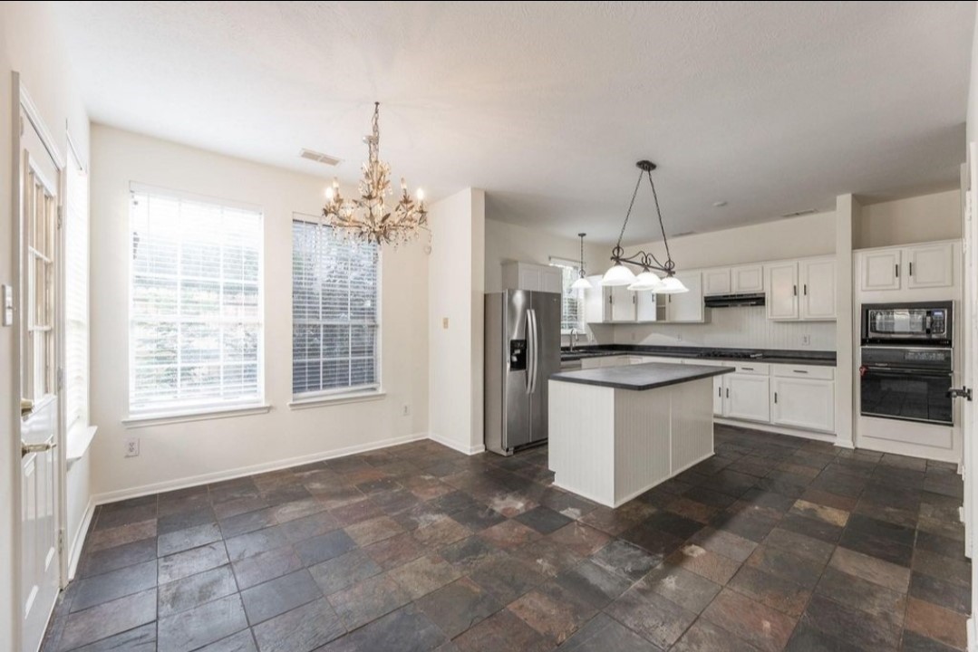 2515 Falcon Ridge Street Pearland, TX 77584 - Photo 13 of 31 a kitchen with kitchen island granite countertop a stove a sink a counter space and cabinets