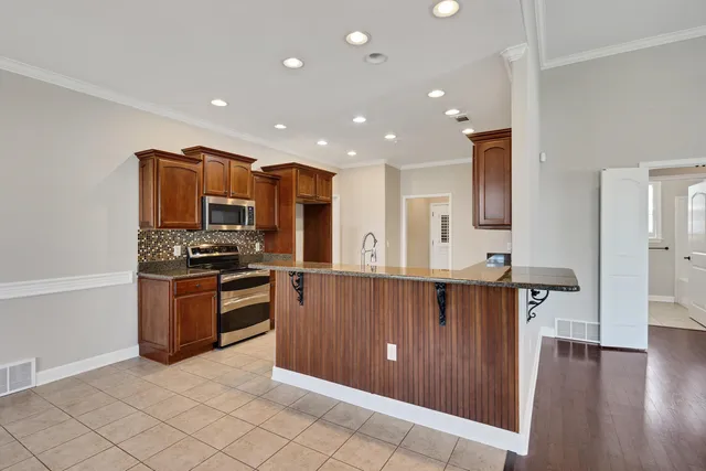 a kitchen with stainless steel appliances kitchen island granite countertop a refrigerator and a stove top oven