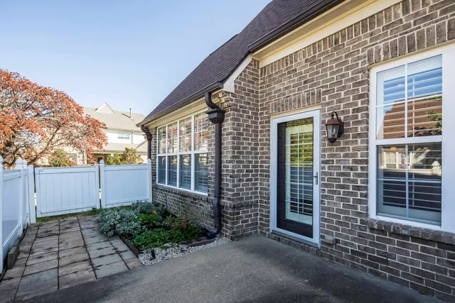 a view of a brick house with plants and wooden fence