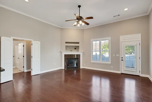 a view of an empty room with a window and wooden floor