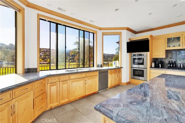 a large kitchen with kitchen island granite countertop a large window and a sink