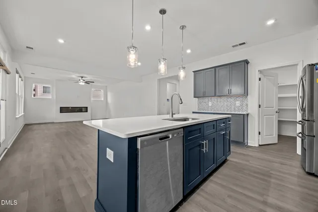 a kitchen with kitchen island granite countertop a sink cabinets and stainless steel appliances