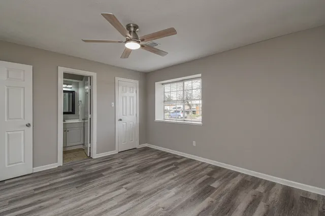 an empty room with wooden floor fan and windows