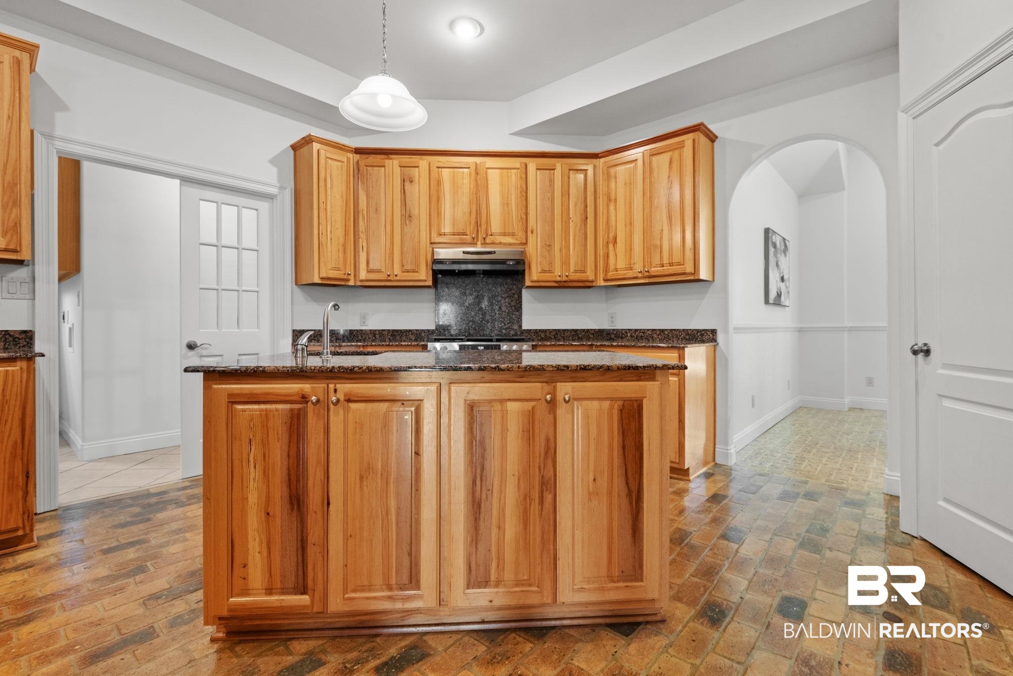 29634 St George Street Daphne, AL 36526 - Photo 17 of 47 Kitchen with arched walkways, a kitchen island with sink, dark stone countertops, and brick floors