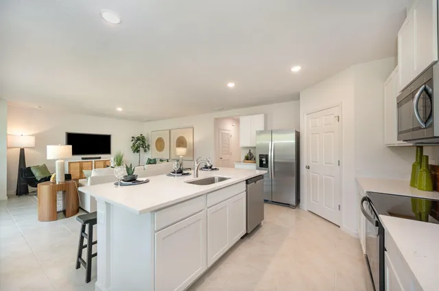 a view of a kitchen with kitchen island a sink stainless steel appliances and cabinets