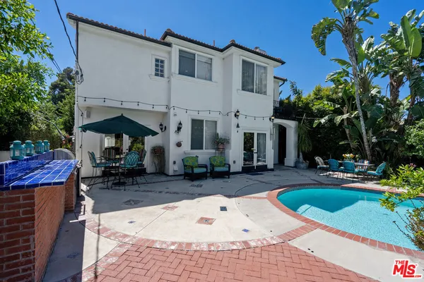 a view of a white house with a yard patio and swimming pool
