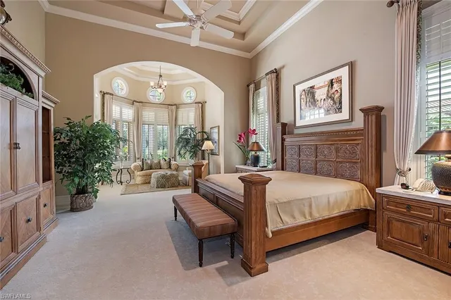 a spacious bedroom with a bed a mirror on dresser and a large window