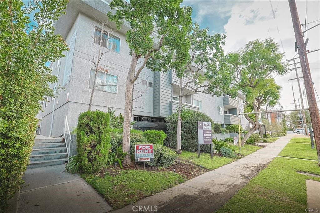 4406 Cahuenga Boulevard, Unit 202 Toluca Lake, CA 91602 - Photo 15 of 16 a view of a house with brick walls and a yard with plants and large trees