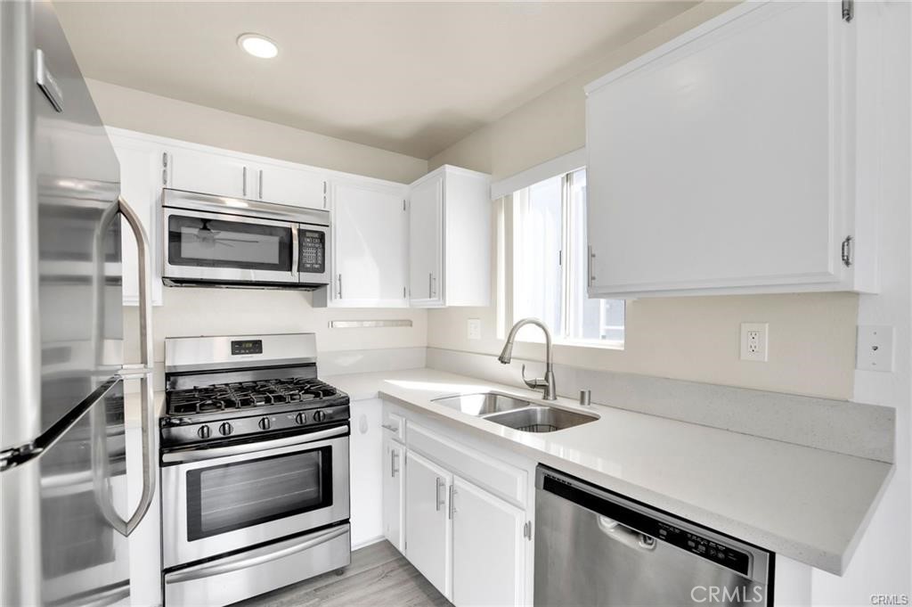 4406 Cahuenga Boulevard, Unit 202 Toluca Lake, CA 91602 - Photo 7 of 16 a kitchen with sink a microwave a stove and cabinets